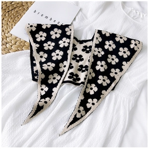 Detailed close-up of knitted flower pattern on a black and beige bicolor scarf shawl