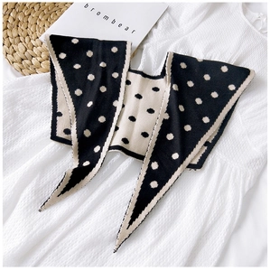 Detailed view of polka dot knitted faux collar scarf on white textured clothing