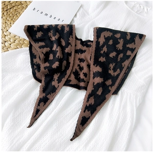 Detail of leopard print knitted shawl draped over a white dress on a natural background