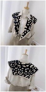 Detail of black knitted shawl with beige abstract patterns shown on a mannequin