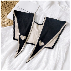 Detail of knitted collar featuring black and beige heart patterns on a large pointed lapel
