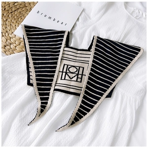 Flat lay of a beige and black knitted shawl with geometric patterns on a white dress