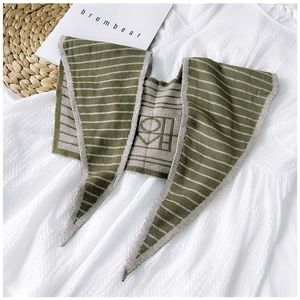 Detail of green knitted striped shawl scarf draped over a white dress with geometric pattern