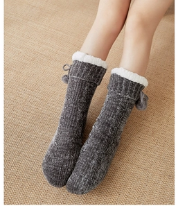 Close-up of gray coral fleece floor socks with twist pattern and bow tie plush balls