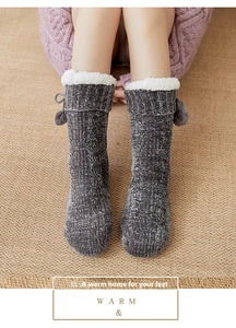 Close-up of gray cable knit floor socks with thick white fleece lining and pom-pom ties