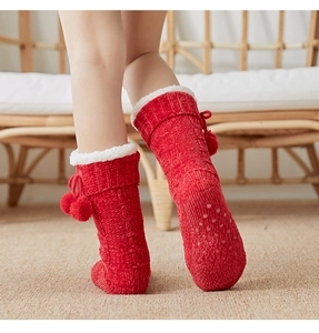 Detail of red knit home socks with white plush trim and non-slip grippy soles