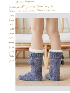 Detail of dark blue cable knit floor socks with plush fleece lining and decorative pompoms
