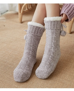 Close-up of grey knitted floor socks with white faux fur trim and decorative pom-poms