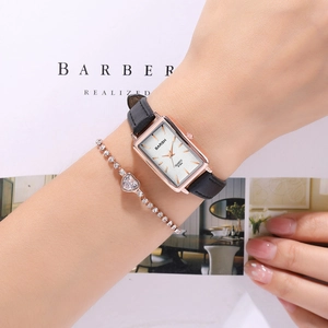 Close-up of elegant rose gold rectangular watch with black leather strap and heart bracelet