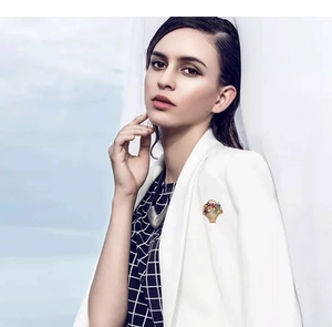 Close-up of golden flower basket brooch with colorful gemstones on a white suit lapel