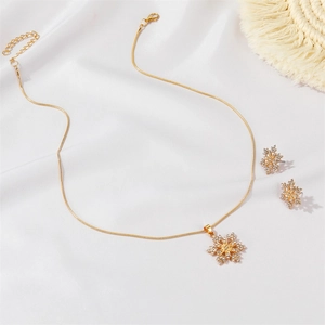 Details vom goldenen Schneeflocken Schmuckset mit Kristallen auf weißem Grund