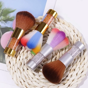 Detailed view of colorful nail dust brushes with rhinestone filled handles on a mat