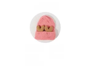 Detail of cute pink knitted winter hat featuring plush brown reindeer antlers decoration