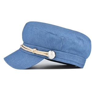 Detail of blue denim baker boy hat featuring white braided rope and silver metal button