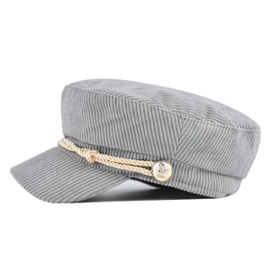 Close-up of grey corduroy octagonal cap showing woven rope and golden metal button detail