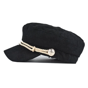 Detail of black corduroy newsboy cap showing gold twisted rope and embossed metal buttons