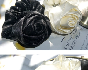 Close-up of silk-like satin rose flower scrunchies in cream and black showing detailed fabric texture