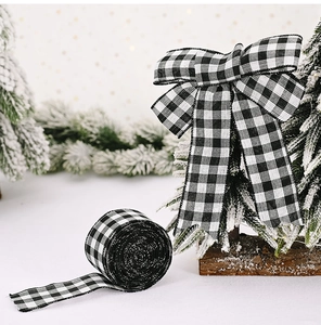 Close-up of black and white gingham ribbon bow on a pine branch with soft holiday lighting