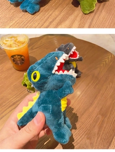 Detailed view of cute plush dinosaur keychain with soft blue fabric and yellow fin details