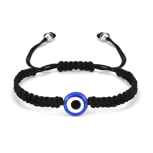 Close-up of hand-woven black cord bracelet with blue evil eye charm and silver beads
