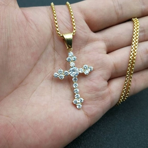 Gros plan détaillé d'un pendentif croix en titane doré serti de pierres de zircone