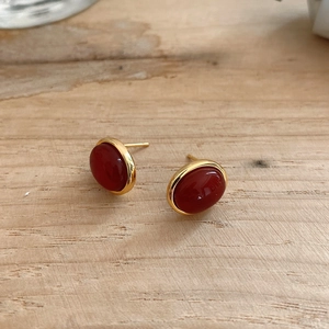 Detailed view of 925 silver oval red agate earrings with gold plating on wood background
