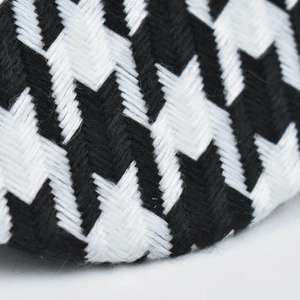 Gros plan sur la texture du tissu en coton à motif pied-de-poule noir et blanc du béret