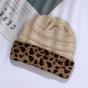 Chic knit beanie with leopard print cuff shown on a textured white background