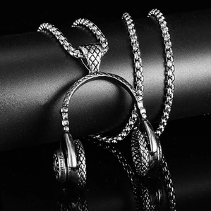 Dramatic close-up of a stainless steel headphone pendant necklace with woven metal chain