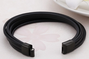 Macro detail of multi-layer black braided leather bracelet with black magnetic clasp