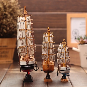 Three Mediterranean style wooden sailing ship models in various sizes on a table