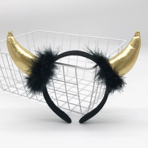 Detail of golden devil horns headband featuring black feather trim for festive party