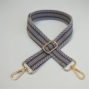 Detail of adjustable geometric woven strap with gold metal hardware on white background
