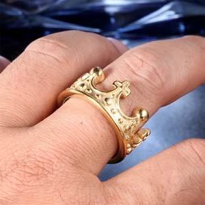 Close-up of golden stainless steel crown ring with cross detail on a model hand