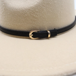 Detail of wool fedora hat featuring a beige felt finish and golden horseshoe buckle
