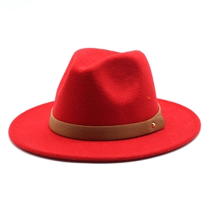 Detail of red fedora hat featuring a brown leather band and gold metallic stud detail