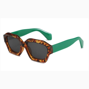Fashionable tortoiseshell hexagonal sunglasses with bright green temples on white background