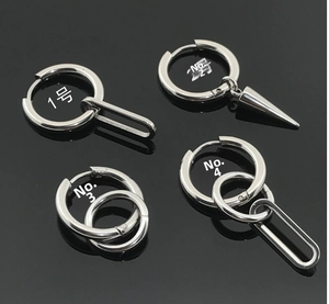 Macro view of four minimalist stainless steel hoop earrings with spiked cone pendants