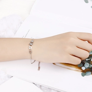 Minimalist silver adjustable bracelet with LOVE square pendants worn on a model's wrist