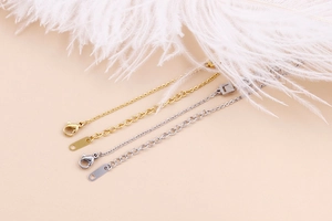 Dettaglio di bracciali regolabili in oro e argento con chiusura a moschettone e catena