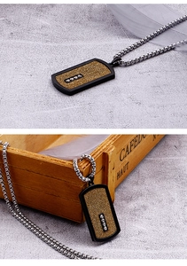 Close-up of matte gold rectangle dog tag necklace with black border and four small diamonds
