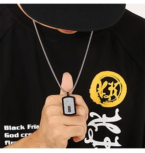 Close-up of a men's black and silver rectangle tag pendant on a steel chain necklace
