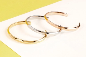 Dettaglio di tre bracciali My Love a forma di C in oro, argento e oro rosa lucido
