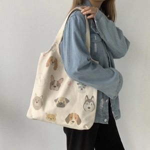 Detailed close-up of cream canvas tote bag featuring cute cartoon dog head illustrations