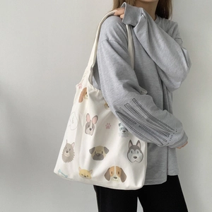Detailed shoulder view of a white canvas tote bag featuring various cute dog illustrations