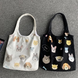 Detailed flat lay of black and cream canvas tote bags with various cartoon dog portraits