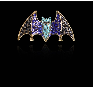 Detailed macro view of bat brooch featuring blue gradient rhinestones on gold base