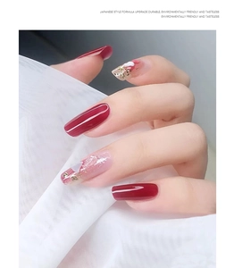 Japanese style nail art with deep red polish and golden foil heart details on sheer nails