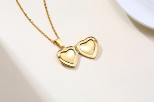 Detailed close-up of an openable gold heart locket pendant on a delicate link chain