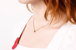 Primo piano della collana in oro rosa minimalista con ciondolo a cubo geometrico
